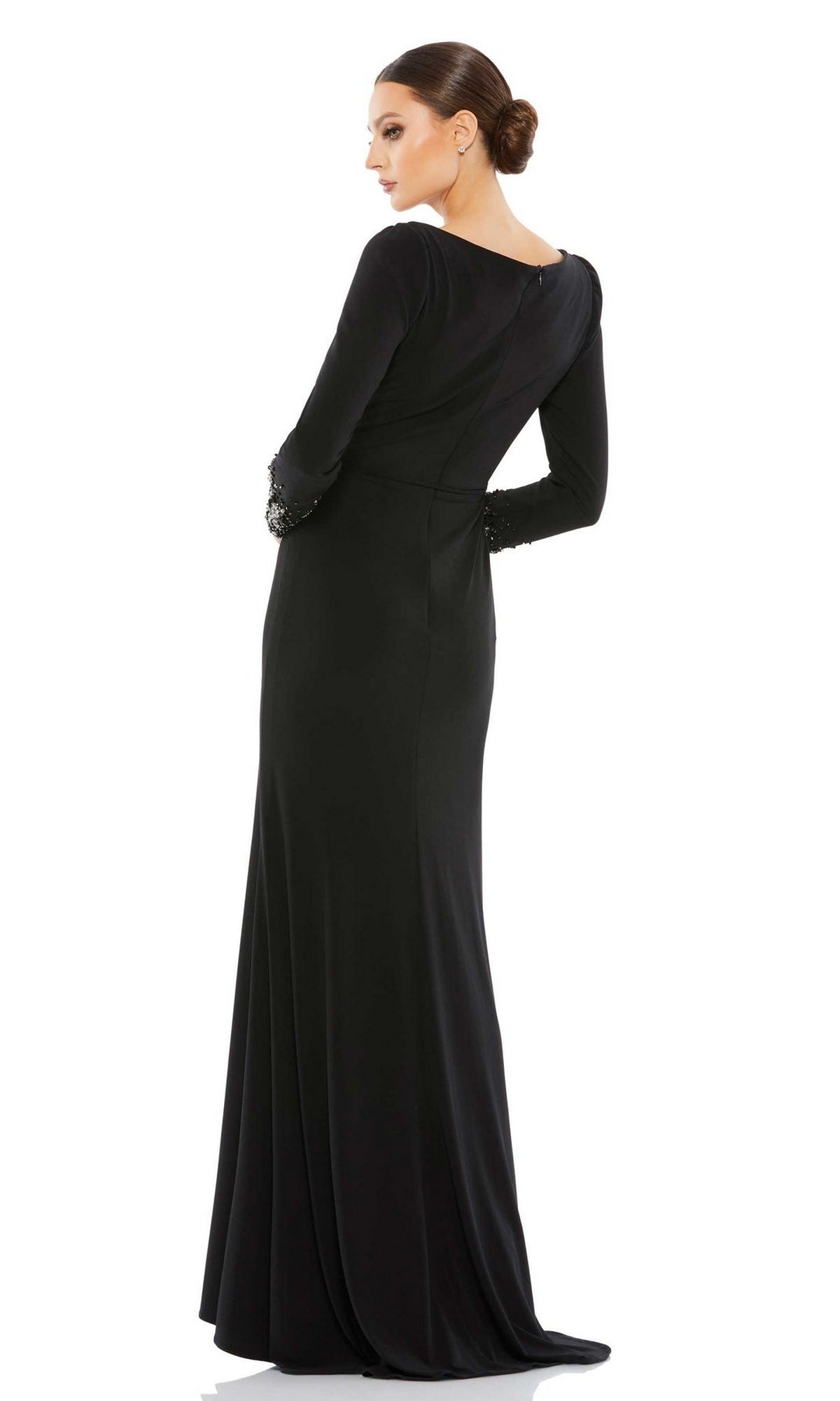 A woman stands facing away in the Long Formal Dress 55712 by Mac Duggal, a fitted black gown with long sleeves and subtle beaded cuffs for an elegant touch.